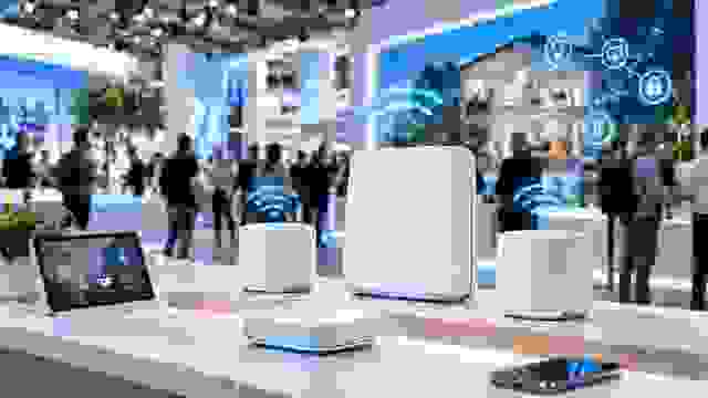 Moderne Router- und Mesh-Geräte auf einem Technik-Messestand mit dargestellten WLAN-Verbindungen