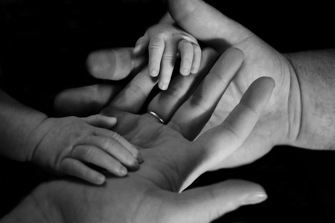 Babyhand in einer Erwachsenenhand als Symbolbild für Pflegeeltern