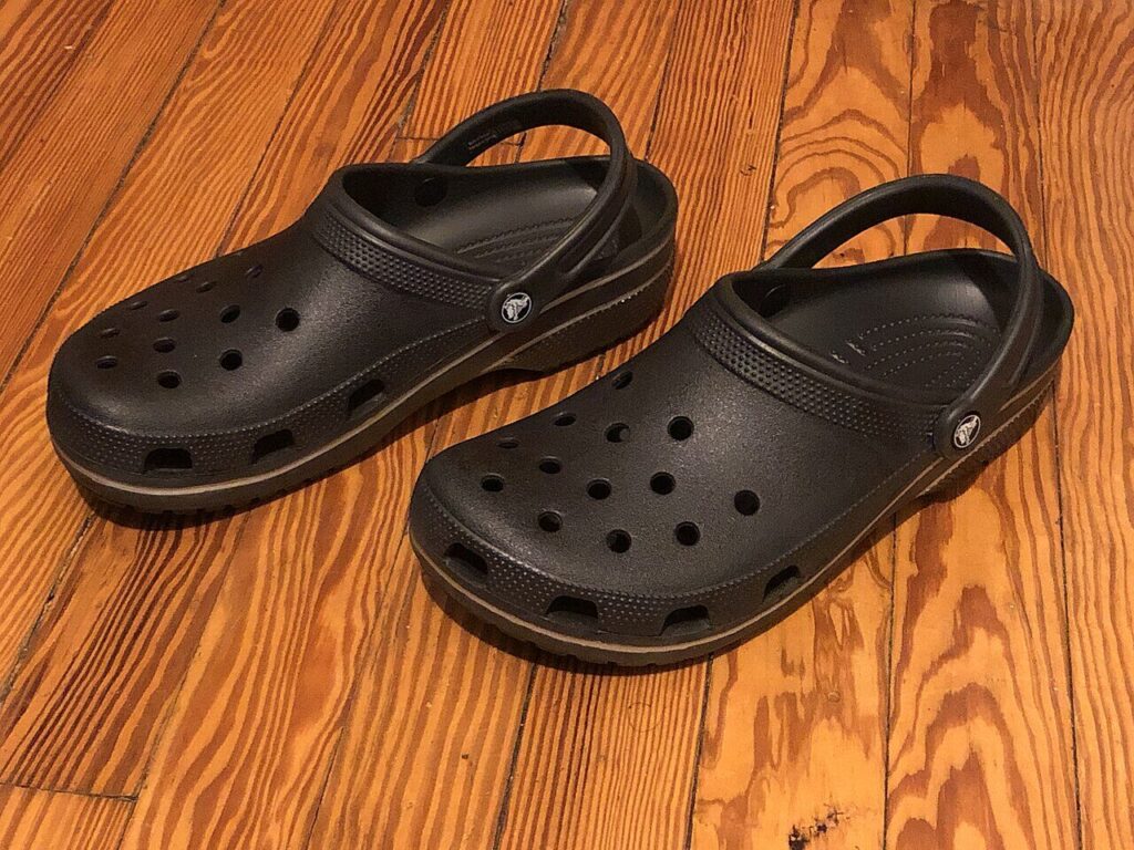 Ein Paar schwarze Crocs-Kunststoffschuhe mit den charakteristischen Löchern