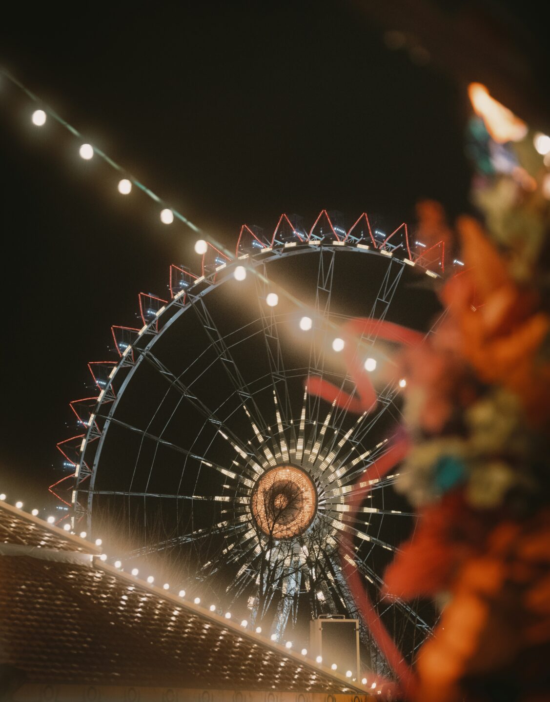 Beleuchtetes Riesenrad auf einem Jahrmarkt bei Nacht – Symbolbild