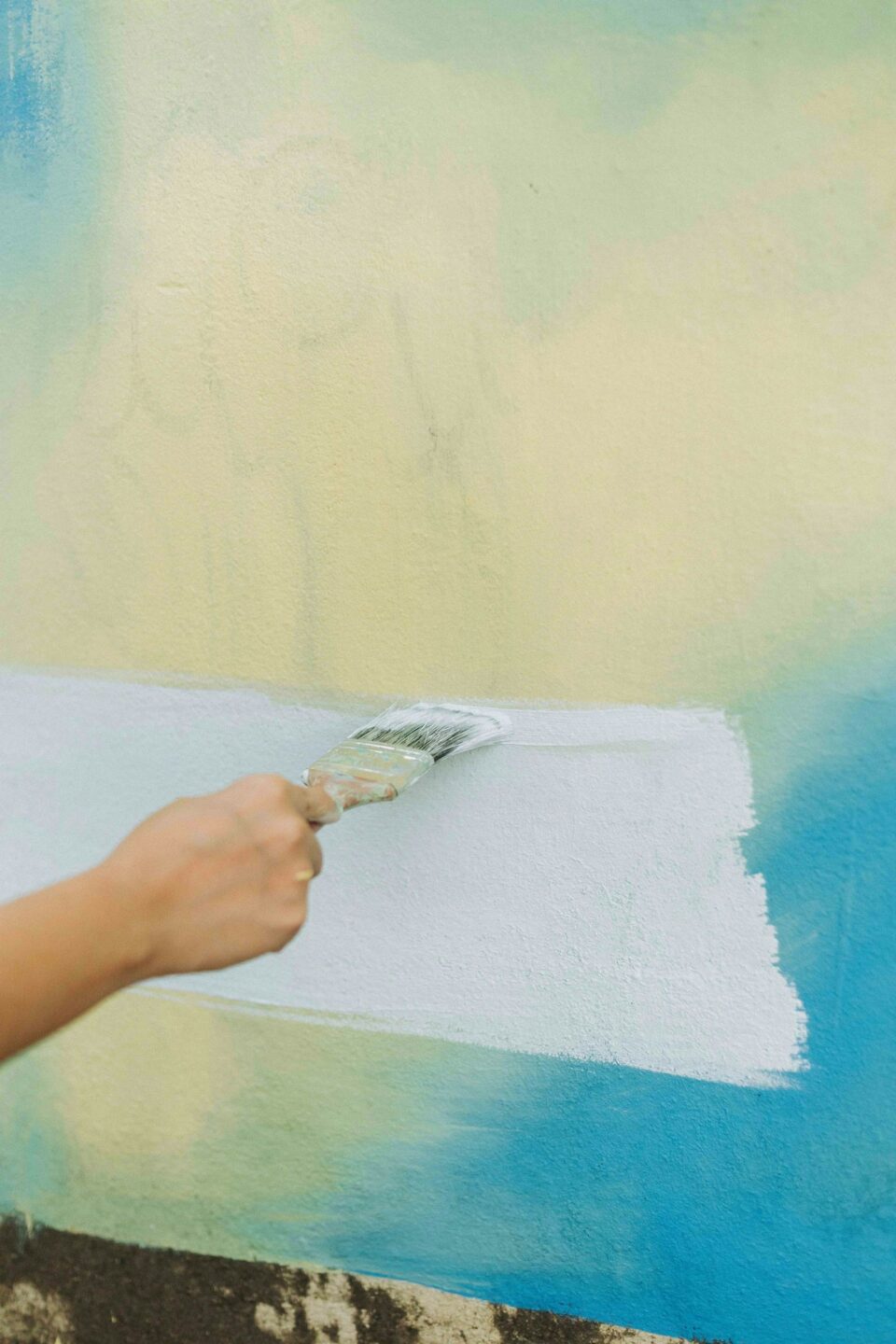 Eine Person streicht eine Wand mit einer Farbrolle